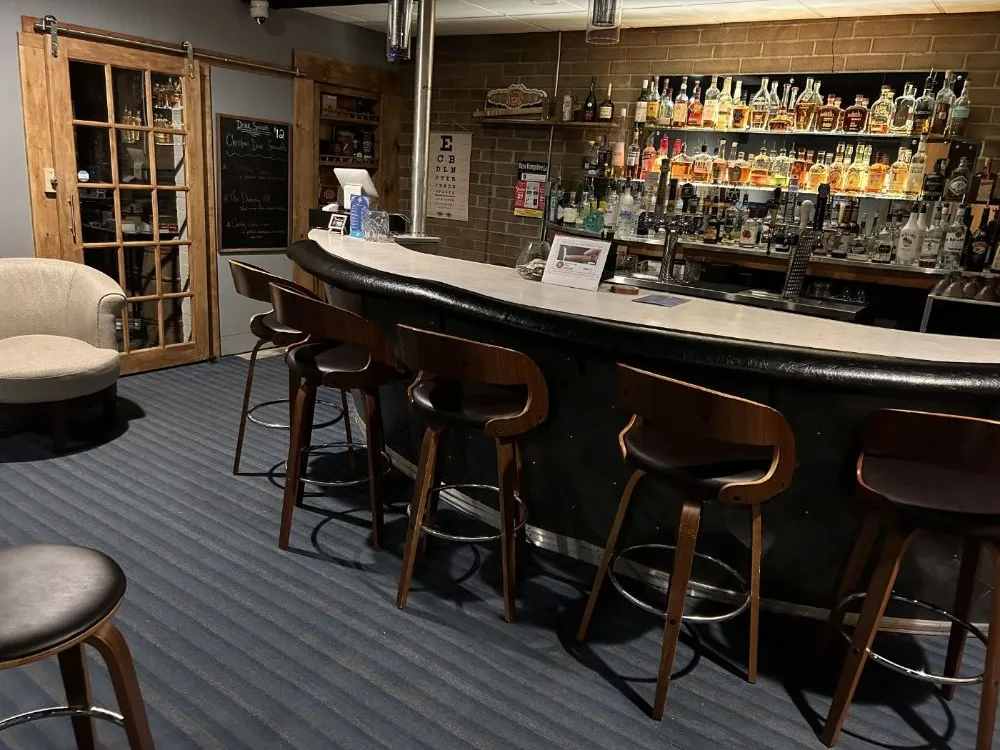 The Den cocktail bar at Red Fox Inn — brick walls, retro stools at the bar counter, conversation lounge in warm light